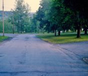 Looking south on School Drive, the HS is on the right and the barber shop is on the left. Not much has changed here. M-8